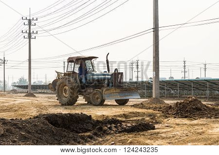Petchaburi, Thailand - February 20, 2016: One worker drives wheel dozer in the under construction solar farm on February 20, 2016 in Petchaburi, Thailand
