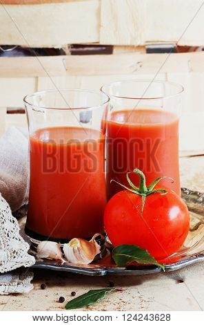 Ripe tasty tomatoes and glass of tomato juice on the old wooden background. Rustic style. Healthy food and drink concept. Selective focus