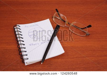 ballpoint pen glasses and an open notebook lying on the table