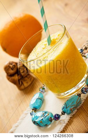 Orange smoothie in a glass. Beads and netsuke. Vertical shot.
