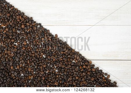 A wooden surface half backfilled with coffee beans on diagonally