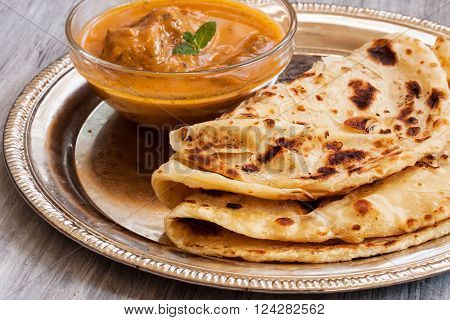 Indian layered Paratha roti kerala porotta with chicken curry on the side