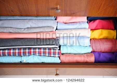 Neatly folded clothes in wooden drawer
