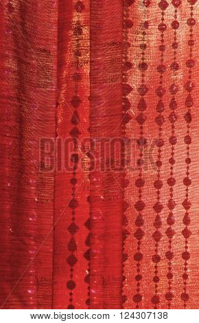 Closeup of red Indian Sari silk curtain with hanging beads/Background of Red Indian sari curtain with hanging beads