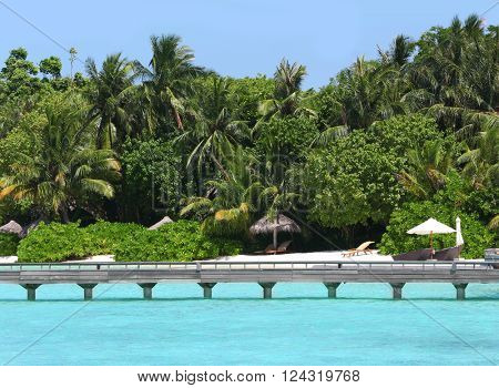 View of tropical Baros Maldives with sand beach and wooden bridge