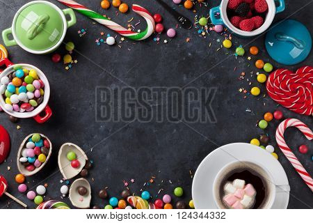 Colorful candies and coffee cup frame on stone background. Top view with copy space