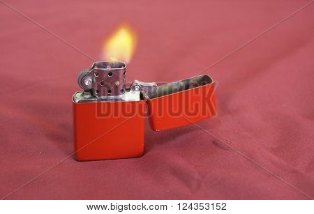 red gasoline lighter with flame on red background