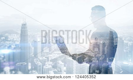 Double exposure stylish businessman wearing black shirt and glasses.Banker holding contemporary notebook hands, work online banking.Panoramic view modern skyscraper city background. Wide, soft light