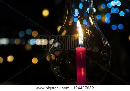A candle burning in a hurricane candle holder