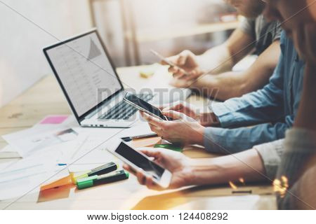 Digital world. Photo young business managers crew working with new startup project.Notebook on wood table. Using modern smartphones, typing message, analyze plans screen.