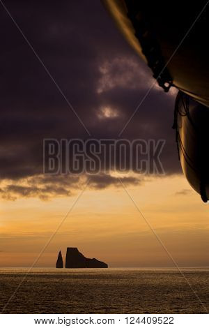 Sunset with a small island on the horizon. Life boats in the foreground. Near San Cristobal Island Ecuador.