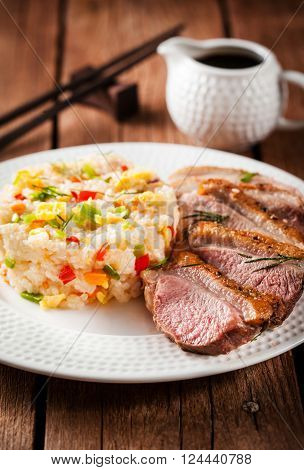Asian style food - fried duck breast and jasmine rice with vegetables and eggs