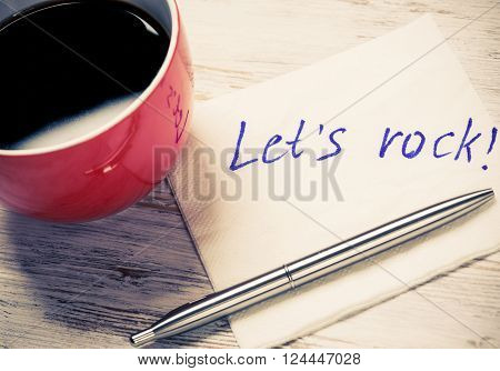Cup of coffee and napkin with writings on table
