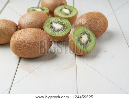 Pile of multiple kiwifruits or chinese gooseberries over the white colored wooden boards surface