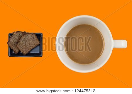 A hot dup of coffee and cake on a colored background