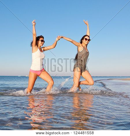 Two pretty girls having fun running on the beach on vacation