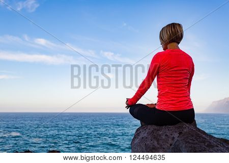 Woman meditating in yoga pose ocean view beach and rock mountains. Motivation and inspirational fit and exercising. Accomplished female yogi practice yoga. Healthy lifestyle outdoors in nature concept.