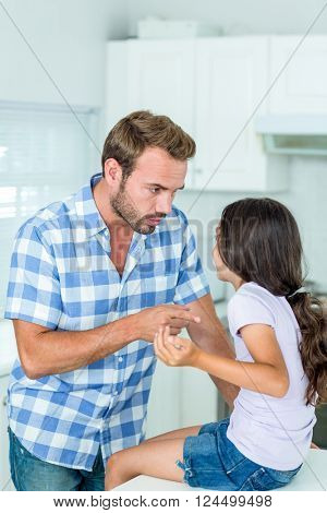 Father pointing while talking with daughter in kitchen at home