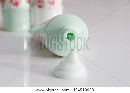 Squirt of cosmetic cream next to an open tube