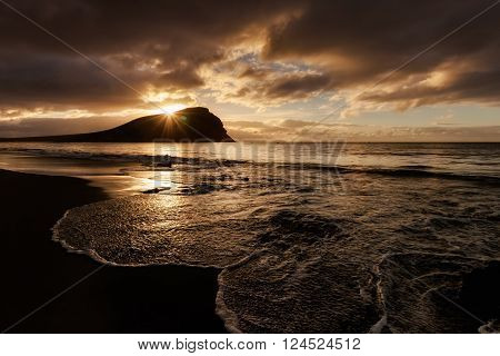 Summer sunrise seascape on tropical island Tenerife, Canary in Spain. Playa de La Tejita beach view on atlantic ocean and Punta Roja rock.