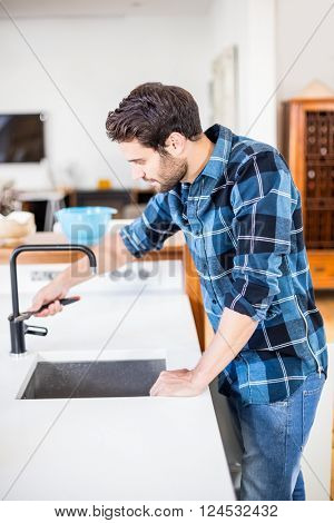 Man fixing tap with tool in the kitchen at home