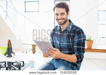 Portrait of happy man using digital tablet in kitchen at home