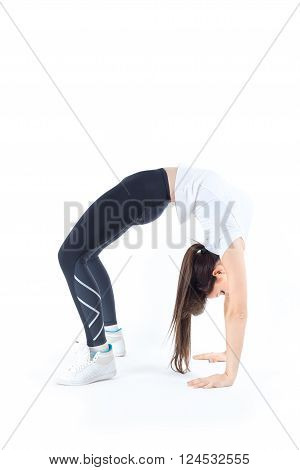 Ductile flexible beautiful young woman makes athletic, gymnastic exercises in crab position isolated on white background