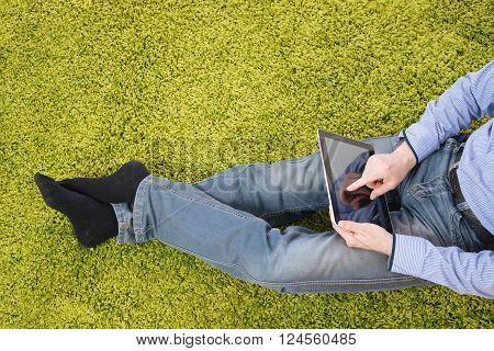 young man sitting on a green carpet with tablet