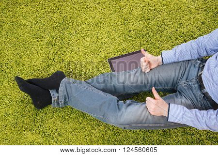 young man sitting on a green carpet with tablet