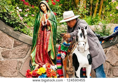 MEXICO CITY - MARCH 30: Man with cellphone next to religious statue in Mexico City on March 30 2013