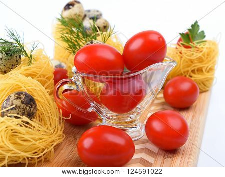 Glass Gravy boat with cherry tomatoes. On a white background.