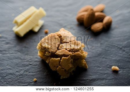 White chocolate and almond brownie on dark background. White chocolade whole almonds and crumbles. Selective focus.