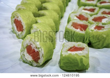 Sliced green salmon sushi on a plate. Cabbage leaves were used to wrap the rolls instead of dried seaweed lavers.