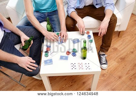 leisure, games, friendship, gambling and entertainment - close up of male friends playing cards and drinking beer at home