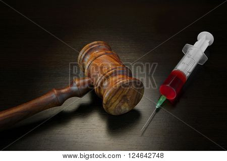 Judges Gavel And Medical Injection Syringe On Black Wooden Background