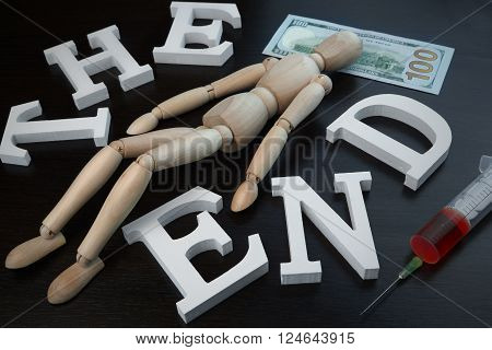Dead or Ill Wooden Human Figurine And Syringe With Red Liquid Laying On One Hundred Dollar Bill On Black Background Closeup