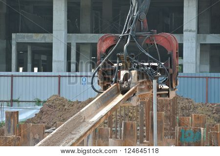 SELANGOR, MALAYSIA - MARCH 12, 2015: Sheet pile cofferdam driven machine at the construction site. This machine drove the sheet pile to the earth using vibrated hydraulic arm. Workers control.