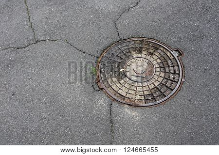Round hatch in urban asphalt road pavement cover sewage hatch.