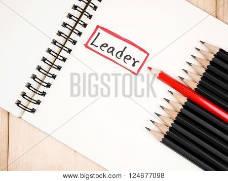Red pencil standout from black pencil and handwriting word Leader on wood background leadership business concept