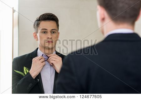 businessman looking in mirror fixing hie tie