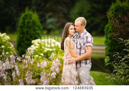 Cute teen couple lovely hugging in the garden flowers.