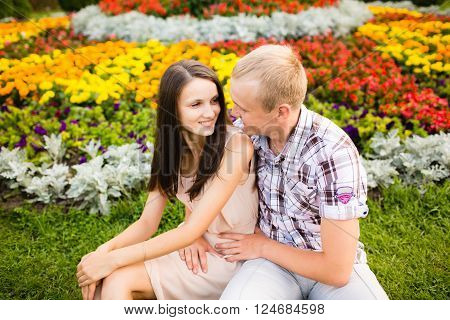 Cute teen couple lovely hugging in the garden flowers.
