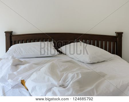 Morning view of an unmade bed in white bedroom