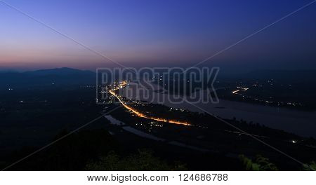 Aerial landscape view of Mekong river with mountain ranges at twilight in Nong Khai Province Thailand. Long exposure shot with street light trails