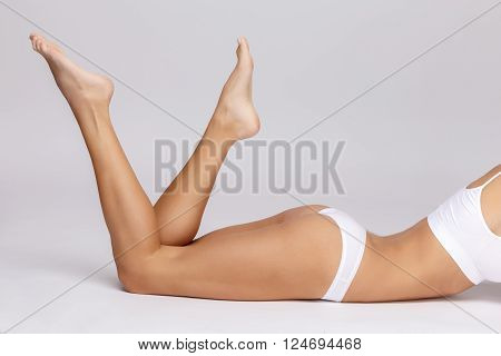 Slim tanned woman's body Isolated over gray background