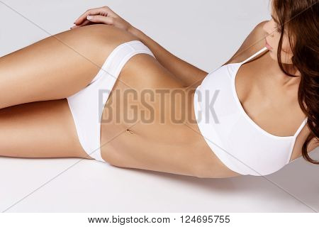 Slim tanned woman's body Isolated over gray background