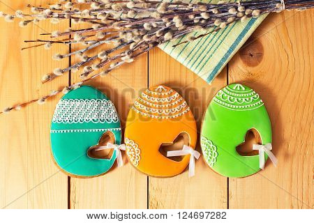 Easter homemade gingerbread cookie willow and yellow end green napkin on wooden table. Colorful toned image top view