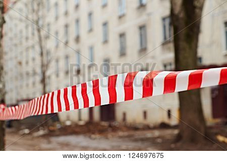 Danger tape waving in the wind in front of empty house ready to be demolished