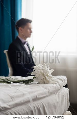 groom with a wedding bouquet is sitting in the chair.