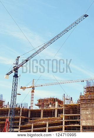 An urban building under contsruction with cranes working to move building materials on site